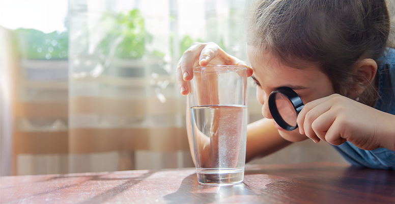 Child looking into glass of contaminated water