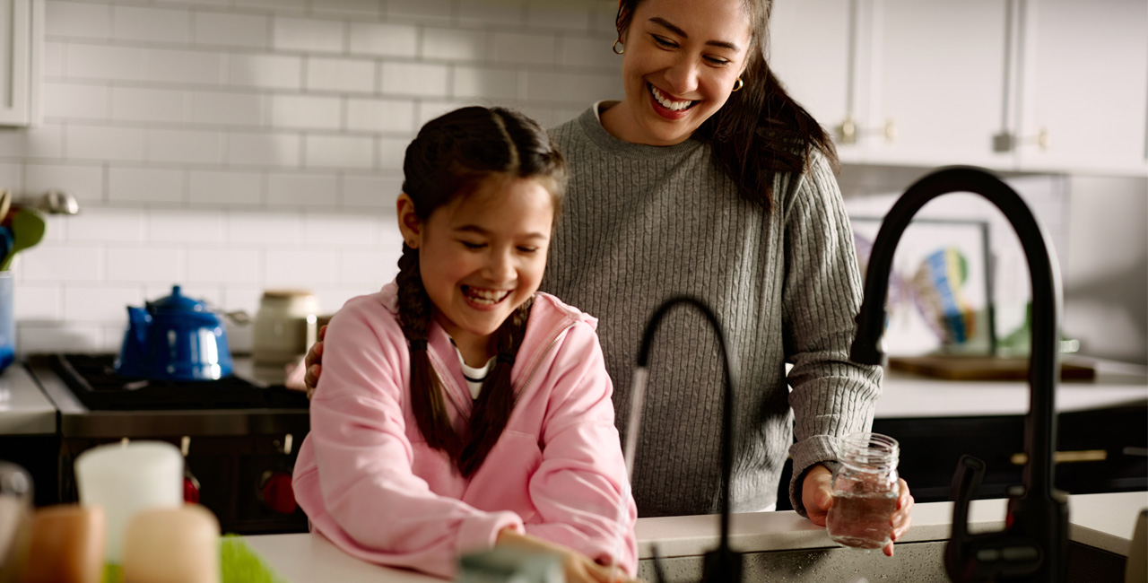 Mom and Daughter washing fruit at sink with Kinetico water.